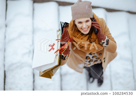 smiling elegant woman in brown hat and scarf talking on phone smiling elegant woman in brown hat and scarf talking on phone 108284530