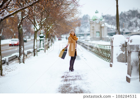 happy modern woman in brown hat and scarf in camel coat happy modern woman in brown hat and scarf in camel coat 108284531