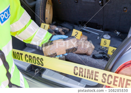 Police officer holding drug package discovered in the trunk of a car 108285830