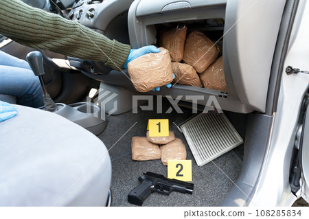 Police officer holding drug package found in secret compartment in a car Police officer holding drug package found in secret compartment in a car 108285834
