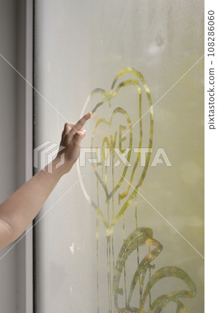 a child's hand draws a heart on the window glass. drawings on the window a child's hand draws a heart on the window glass. drawings on the window 108286060