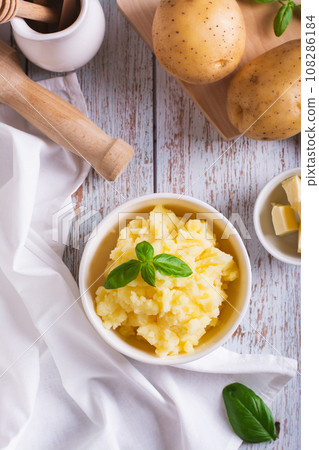 Bowl with delicious homemade mashed potatoes and basil on the table top and vertical view Bowl with delicious homemade mashed potatoes and basil on the table top and vertical view 108286184