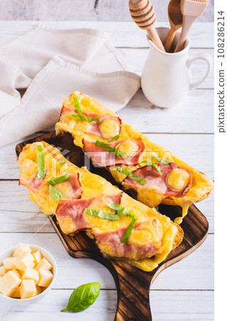 Baguette baked with ham, cheese and basil on a wooden board vertical view 108286214