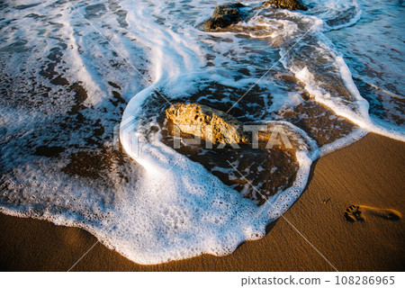 Directly above view of waves breaking on shore at sunset. Directly above view of waves breaking on shore at sunset. 108286965