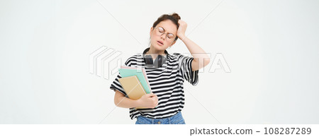 Portrait of young tired student, girl has headache, touching head with troubled face expression, sighing from complicated situation, standing over white background Portrait of young tired student, girl has headache, touching head with troubled face expression, sighing from complicated situation, standing over white background 108287289