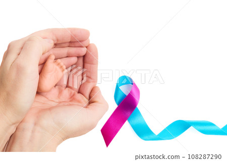 World Prematurity Day on 17th November. Woman hand with a baby feet . Motherhood and care. 108287290