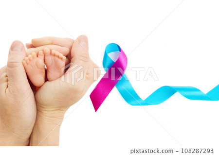 World Prematurity Day on 17th November. Woman hand with a baby feet . Motherhood and care. 108287293