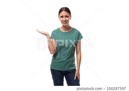 young slender european woman with a ponytail hairstyle dressed in a green t-shirt is puzzled on a 108287397