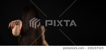 Halloween. A woman with long black hair covering her face points her finger with long red nails at the camera. Copyspace. Halloween witch pointing at you. Concept baner, halloween flyer. 108287424
