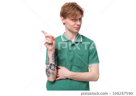 a young smart european guy with red hair with a tattoo on his forearm wears a green t-shirt has an a young smart european guy with red hair with a tattoo on his forearm wears a green t-shirt has an 108287590