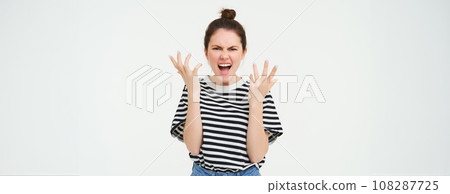 Image of angry woman shouts and shakes hands, stands in casual clothes over white background Image of angry woman shouts and shakes hands, stands in casual clothes over white background 108287725