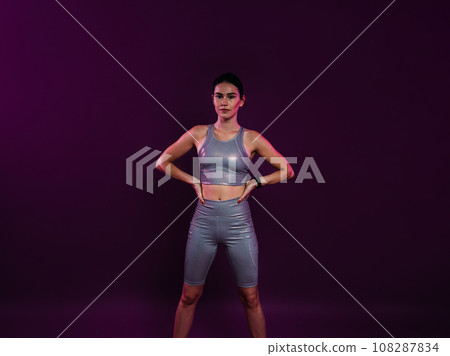 Young confident sportswoman in silver fitness attire with hands on hips Young confident sportswoman in silver fitness attire with hands on hips 108287834