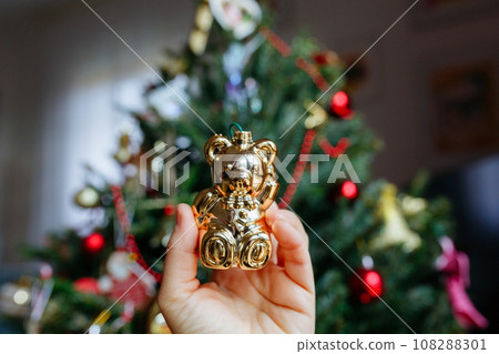 close up view on golden christmas teddy bear toy in front of christmas tree 108288301