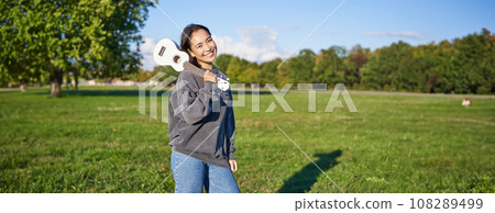 Beautiful korean girl posing with ukulele, young musician playing outdoors in green park on sunny day 108289499