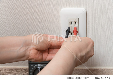 [Housewife measuring outlet voltage with a tester] 108289565