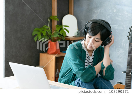 A woman listening to music with headphones A woman listening to music with headphones 108290371