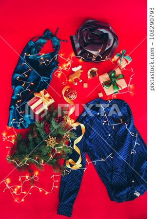 Christmas gifts on red background. Gift boxes with ribbons, branch of a Christmas tree, and clothes. Christmas gifts on red background. Gift boxes with ribbons, branch of a Christmas tree, and clothes. 108290793