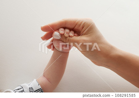 Parents' hands hold the fingers of a newborn baby. The hand of a mother and father close-up holds the fist of a newborn baby. Family health and medical care. Professional photo on white background Parents' hands hold the fingers of a newborn baby. The hand of a mother and father close-up holds the fist of a newborn baby. Family health and medical care. Professional photo on white background 108291585