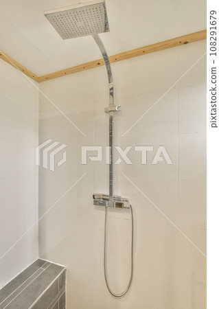 a modern bathroom with white tiles and wood trim on the walls, along with a shower head mounted to the wall 108291679