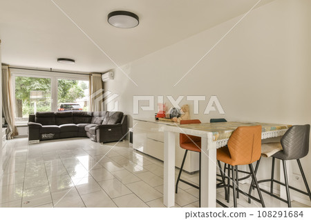 a living room and kitchen area in a house with white tile flooring, two bar stools and an open window a living room and kitchen area in a house with white tile flooring, two bar stools and an open window 108291684