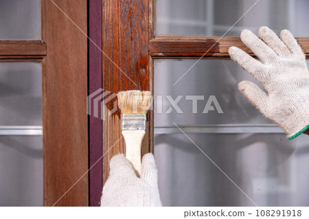 Worker use brush apply wood preserver after sandling the old surface of wooden window 108291918