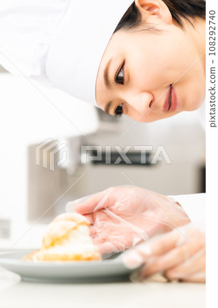 A pastry chef serving cream puffs on a plate 108292740