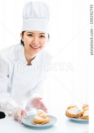 A pastry chef serving cream puffs on a plate 108292745