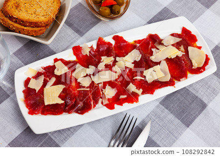 Plate of delicate raw veal carpaccio with cheese 108292842