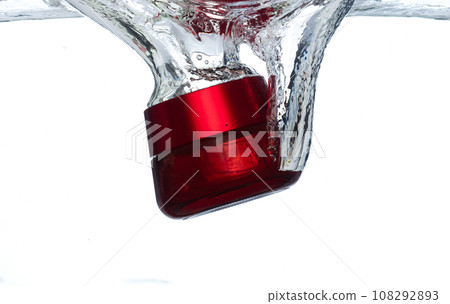 Red Cosmetic container fall into clear water with air bubble. Cosmetic treatment container drop to clear water of freshness. White background isolated freeze element 108292893