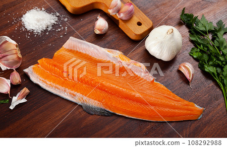 Raw fresh red trout fillet with garlic and greens 108292988