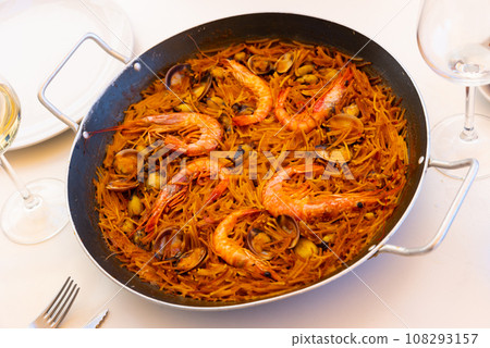 Seafood fideua with mussels, scallops and prawns in paella pan with aioli 108293157