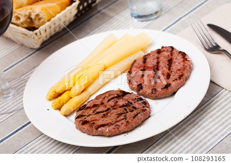 Fried cutlets with boiled asparagus on plate 108293165