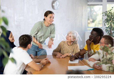 Smiling girl discussing volunteer project with group of associates Smiling girl discussing volunteer project with group of associates 108293224