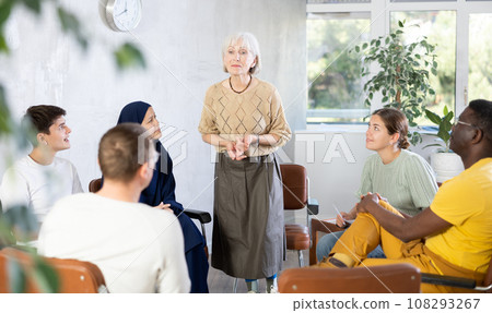 Mature female teacher giving lecture to group of multinational students Mature female teacher giving lecture to group of multinational students 108293267