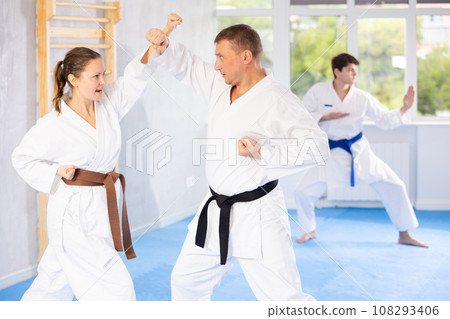 Woman and man in kimono sparring together in sport gym during karate training 108293406