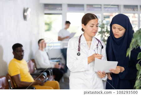 Nurse discusses documents with young Asian woman in veil 108293500