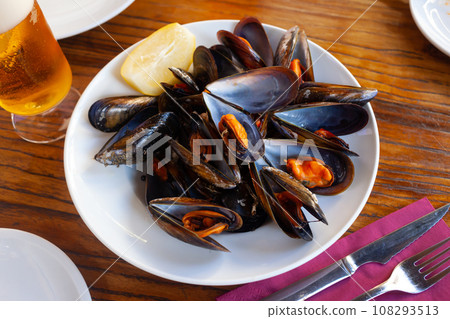 Baked mussels in shells with slice of lemon and beer 108293513