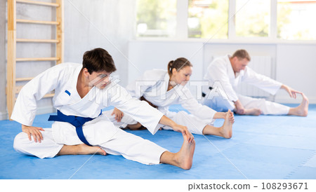 Teacher and followers perform warm-up exercises and legs stretching Teacher and followers perform warm-up exercises and legs stretching 108293671