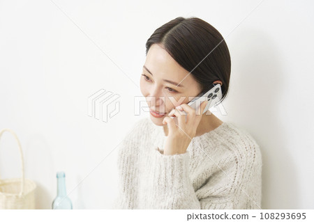 A woman calling on a smartphone in the living room 108293695