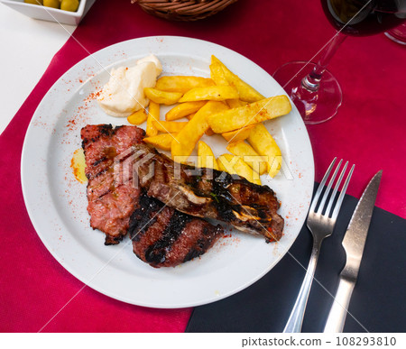 Roasted meat with potatoes served on plate with red wine and some salsa sauce 108293810