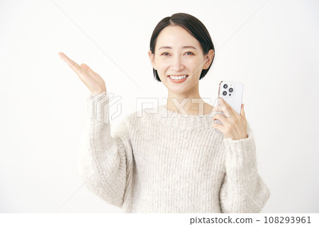 一位女士拿著智慧型手機，用手掌、白色背景指著左側 108293961