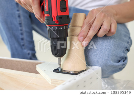man assembling sofa furniture at home using cordless screwdriver man assembling sofa furniture at home using cordless screwdriver 108295349