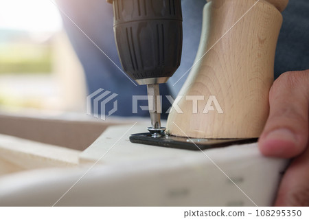 man assembling sofa furniture at home using cordless screwdriver man assembling sofa furniture at home using cordless screwdriver 108295350