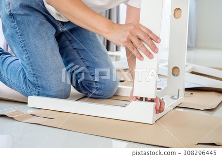 Man assembling white chair furniture at home 108296445