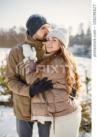 Portrait of romantic couple having fun on winter walk. Man and woman hugging. Family wearing warm jacket and knitted hats. Portrait of romantic couple having fun on winter walk. Man and woman hugging. Family wearing warm jacket and knitted hats. 108296827