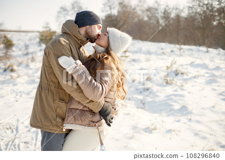 Portrait of romantic couple having fun on winter walk. Man and woman hugging. Family wearing warm jacket and knitted hats. Portrait of romantic couple having fun on winter walk. Man and woman hugging. Family wearing warm jacket and knitted hats. 108296840