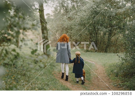 Mother and her daughter playing with dog. Family in autumn park. Pet, domestic animal and lifestyle concept. Autumn time. Mother and her daughter playing with dog. Family in autumn park. Pet, domestic animal and lifestyle concept. Autumn time. 108296858