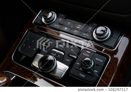 Interior of modern luxury car. Details of automatic transmission gear shift, multimedia control system, car control panel, Air Vent Red emergency button and dashboard inside. Prestige sport automobile Interior of modern luxury car. Details of automatic transmission gear shift, multimedia control system, car control panel, Air Vent Red emergency button and dashboard inside. Prestige sport automobile 108297317