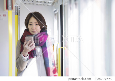 穿著冬衣的中年婦女在火車上看著智慧型手機 108297660