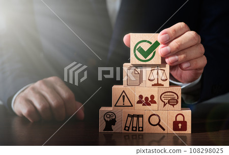 Image of compliance and business management. Comply with laws and regulations. A man stacking wooden blocks on a table 108298025